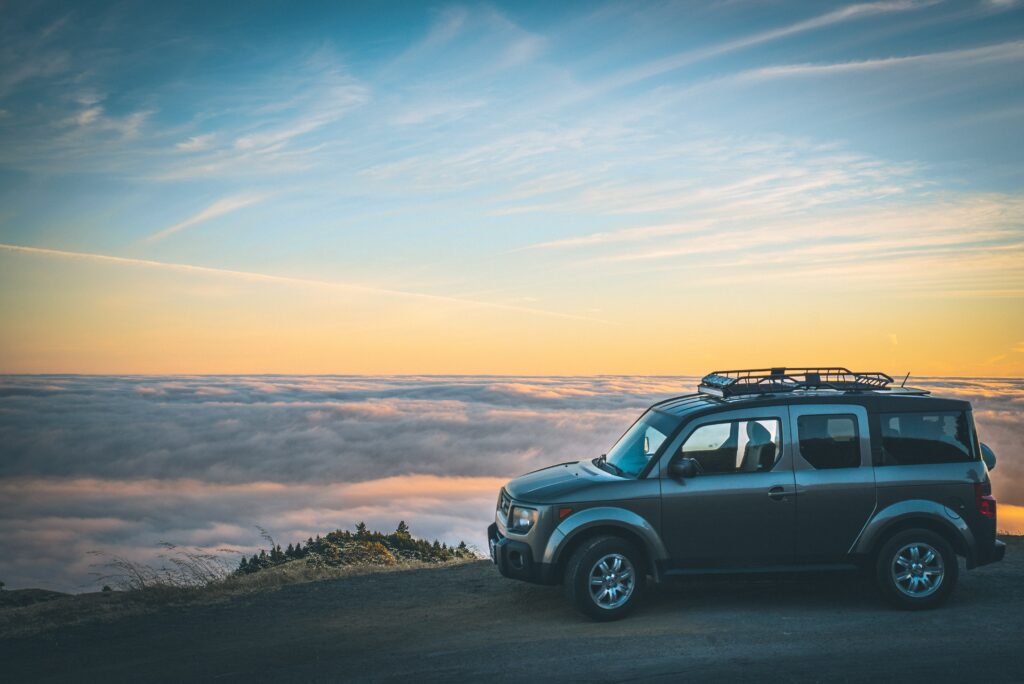 Small minivan in front of a cliff overlooking the sky's sunset in preparation of day trips