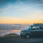 Small minivan in front of a cliff overlooking the sky's sunset in preparation of day trips